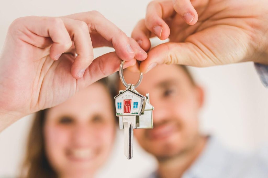 young family holding house keys in front of new home, no visible faces