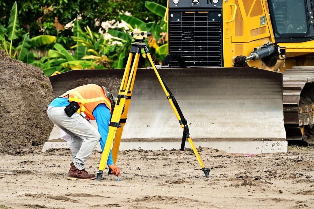 land surveyor using a total station tripod instrument outdoors in a field, no people visible in close-up