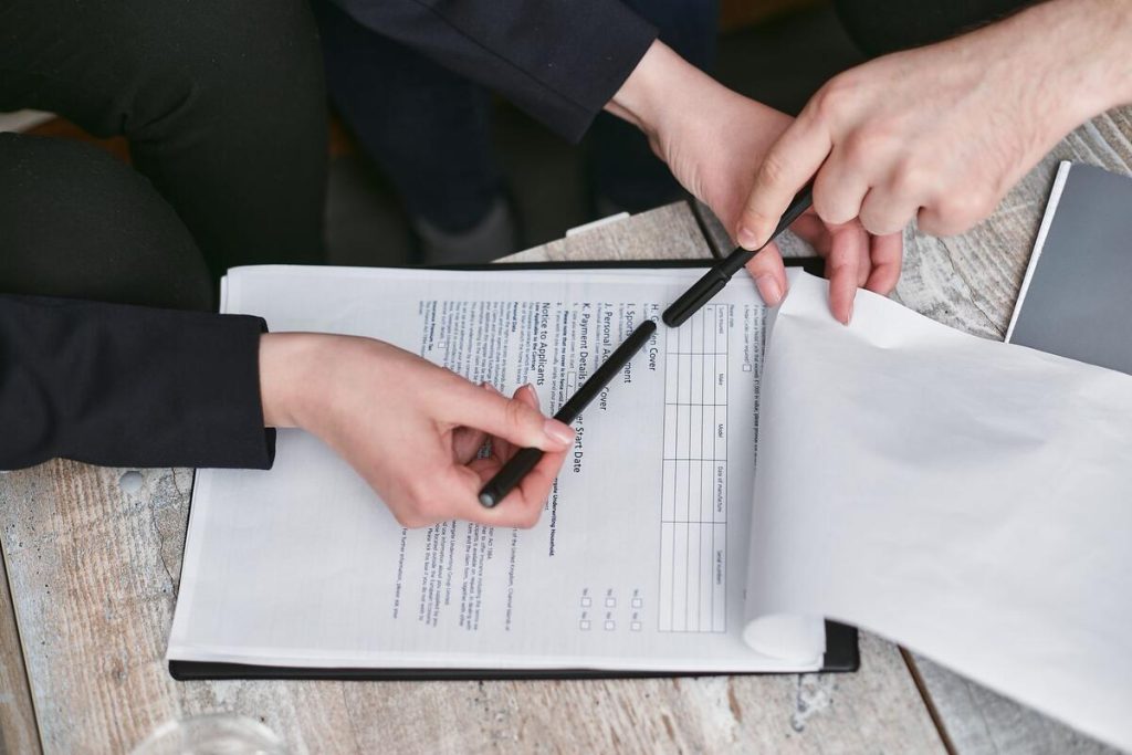 hands reviewing a cadastral extract document with a pen, close up, no faces