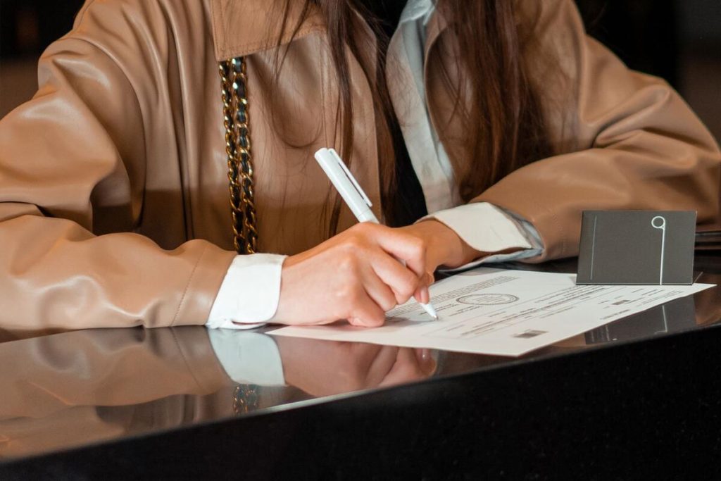 close-up of a hand signing a legal document being certified at a notary desk